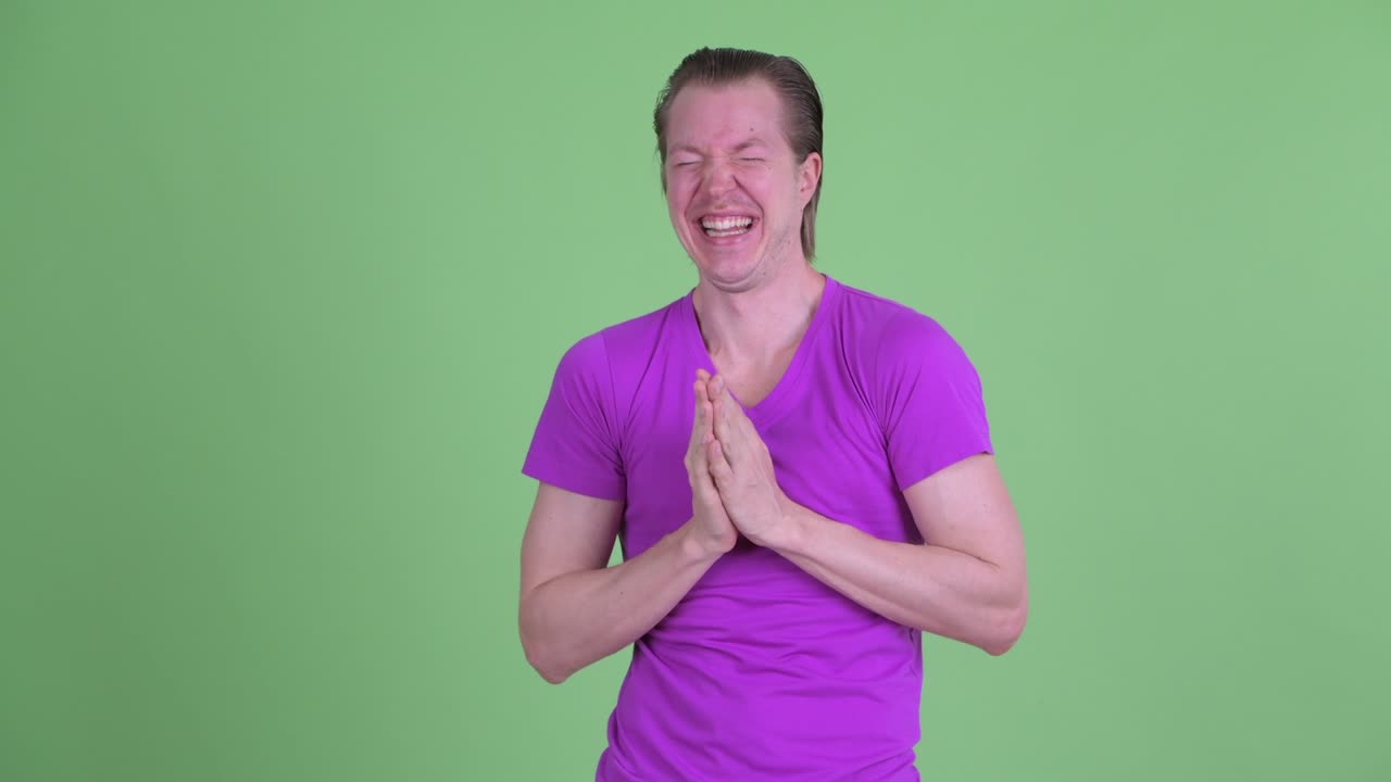 젊은 남자가 웃긴 얼굴을 하고 초록색 배경에 놀이하는 스튜디오