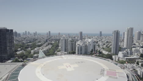 flying over the helicopter landing pad on the roof of the hospitalization tower building at the ichilov hospital center tel aviv, the mediterranean sea in the background - push in shot