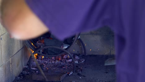 brazos de un hombre avivando el fuego para preparar un asado argentino, cerrar