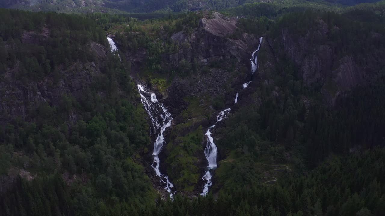 Lush, green Norwegian landscape with cascading waterfalls and rocky terrain
