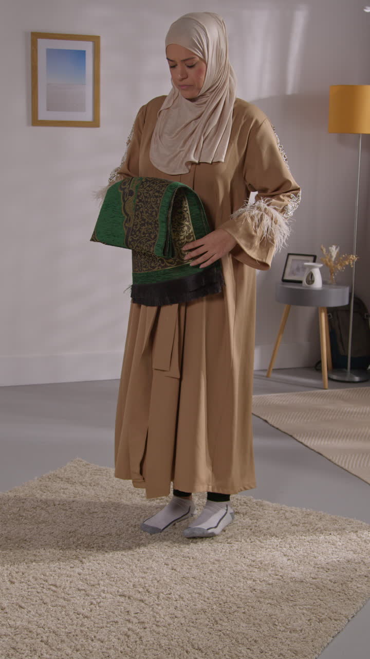 Vertical Video Of Muslim Woman Wearing Hijab At Home Laying Down And Standing On Prayer Mat On Floor