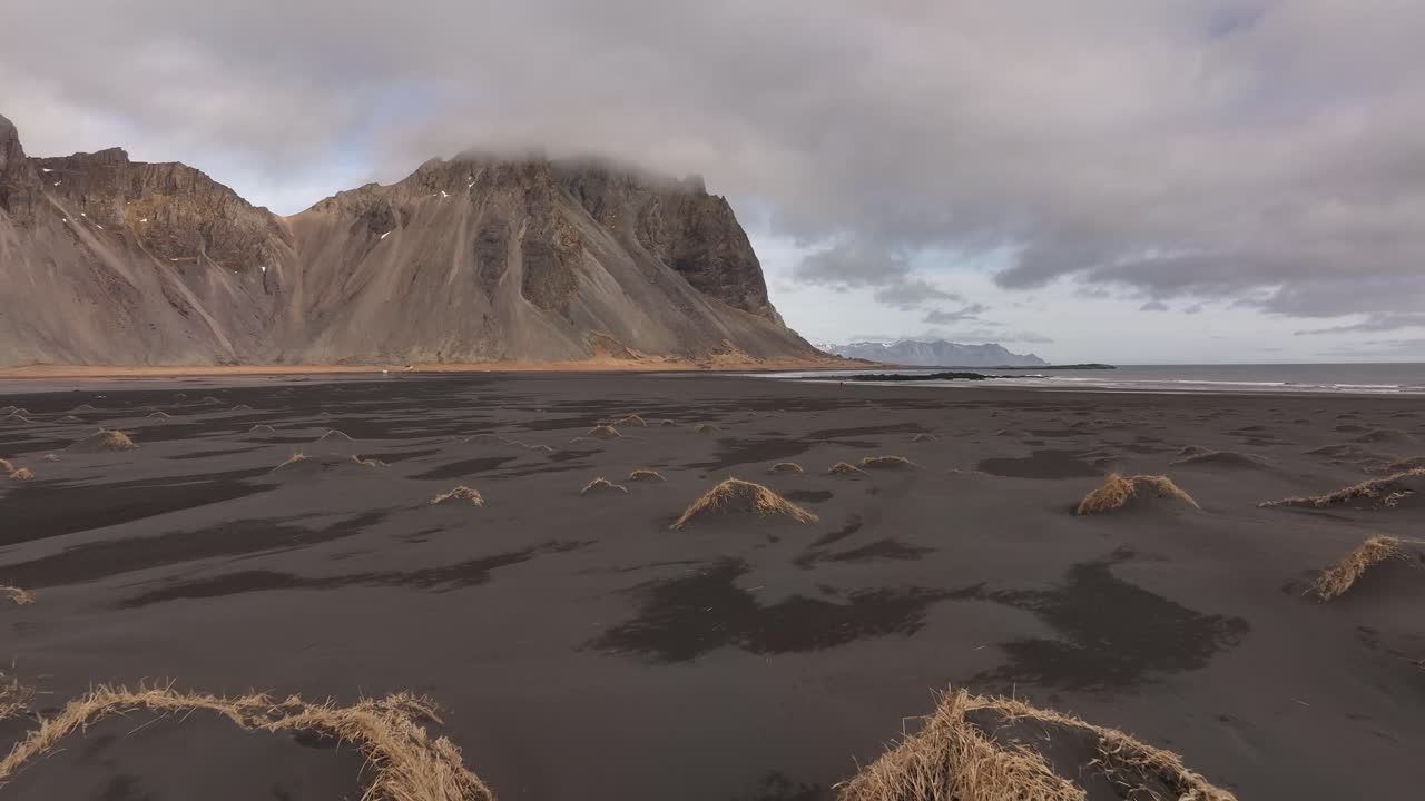 windswept black beach and misty cliffs under moody Icelandic skies