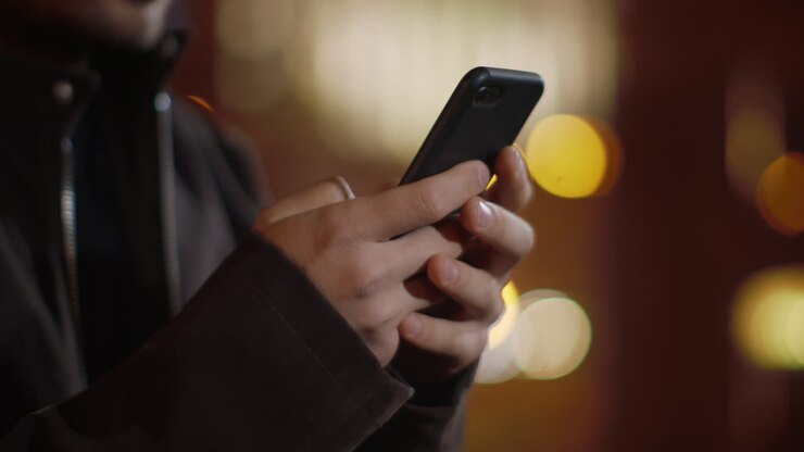 Mani di uomo che digitano sul telefono per strada. Uomo irriconoscibile che scrive un messaggio al telefono.