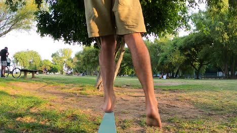 Close-up-man-balancing-on-slack-line-at-park-outdoors