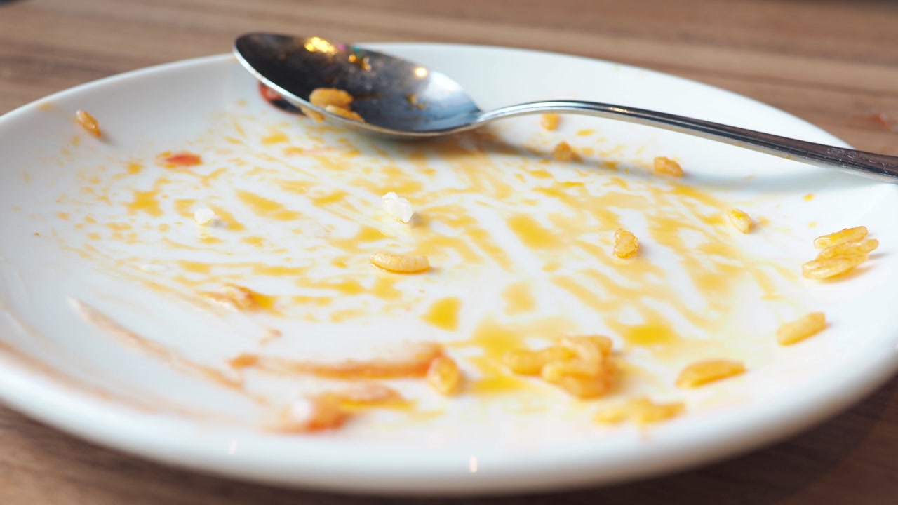 Dirty White Plate with Leftover Food and Spoon After a Meal