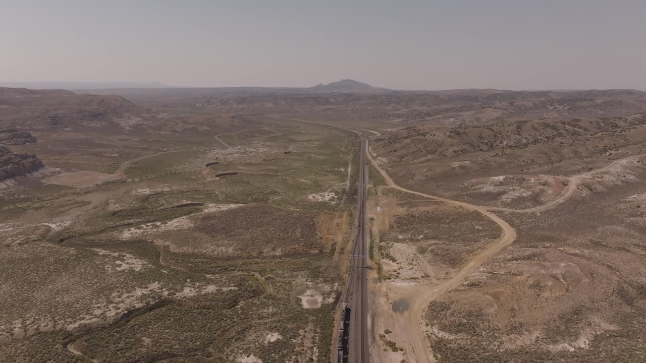 Wide drone shot of a train cutting through the American West