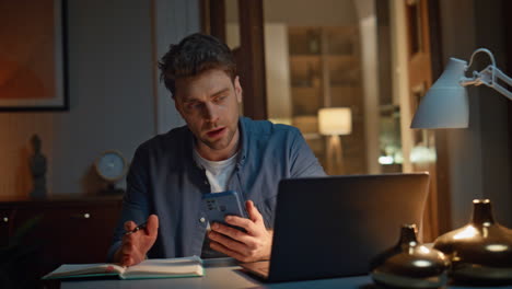 online manager writing notes at late home closeup. calm man videocalling laptop