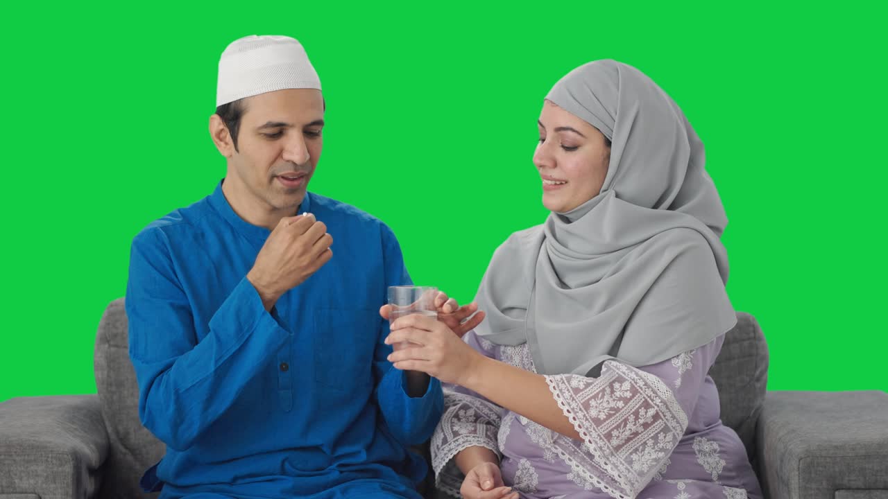 행복한 무슬림 아내가 남편에게 약을 주는 녹색 화면
