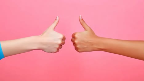 two hands giving a thumbs up sign on a pink background