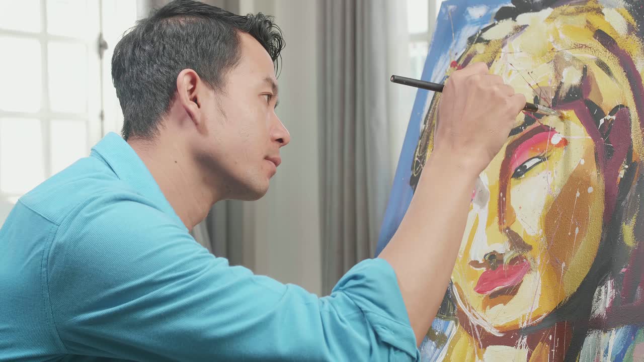 Side View Of An Asian Artist Man Holding Paintbrush Mixed Colour And Thinking Before Painting A Girl'S Face On The Canvas