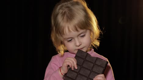 niño atractivo comiendo un enorme bloque de chocolate. chica rubia linda