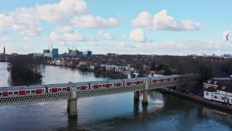 dolly back drone shot of district line london underground train on kew railway bridge