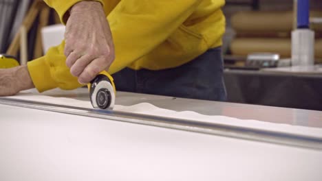 hand of a factory worker cutting fabric with a rotary cutter