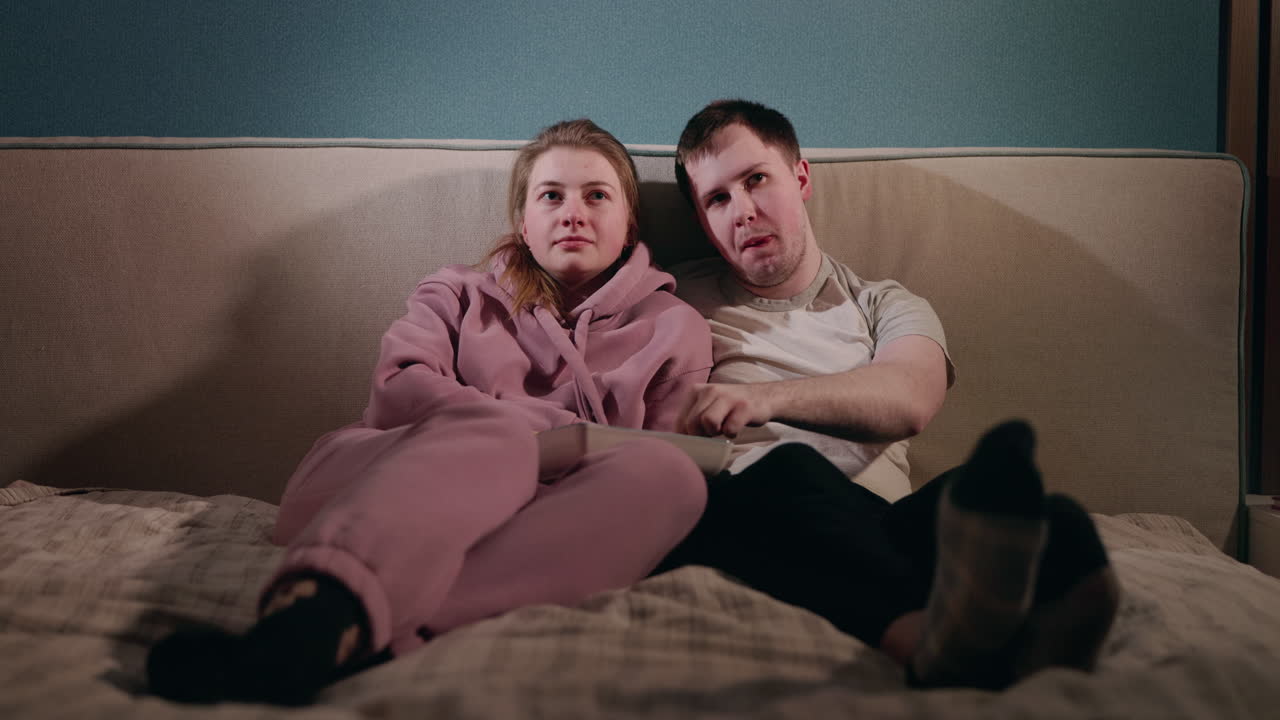 한 부부가 집에서 영화를 보고 휴식을 취하고 있다