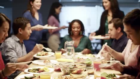 a joyful gathering: friends and colleagues enjoying a delicious meal together at a festive table filled with plates of colorful dishes and refreshing drinks