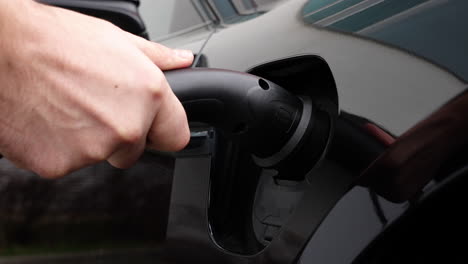 hand connection plug with modern electric car socket on charging station, close up