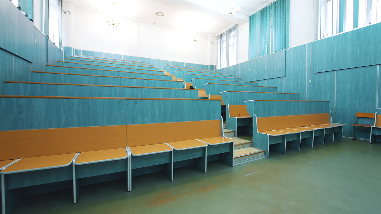 Comfortable classroom without students. Empty auditorium with wooden desks in blue color. Light lecture hall in the University.