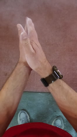 a first-person view of workout preparation, showing feet on a mat and hands being chalked and clapped