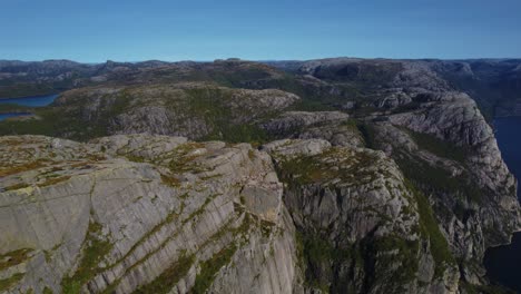 Cinematic aerial footage of Preikestolen Pulpit Rock cliff edge surrounded by fjord waters in Norway