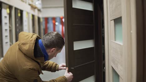 Man-in-hardware-store-choosing-a-door-checking-a-lock