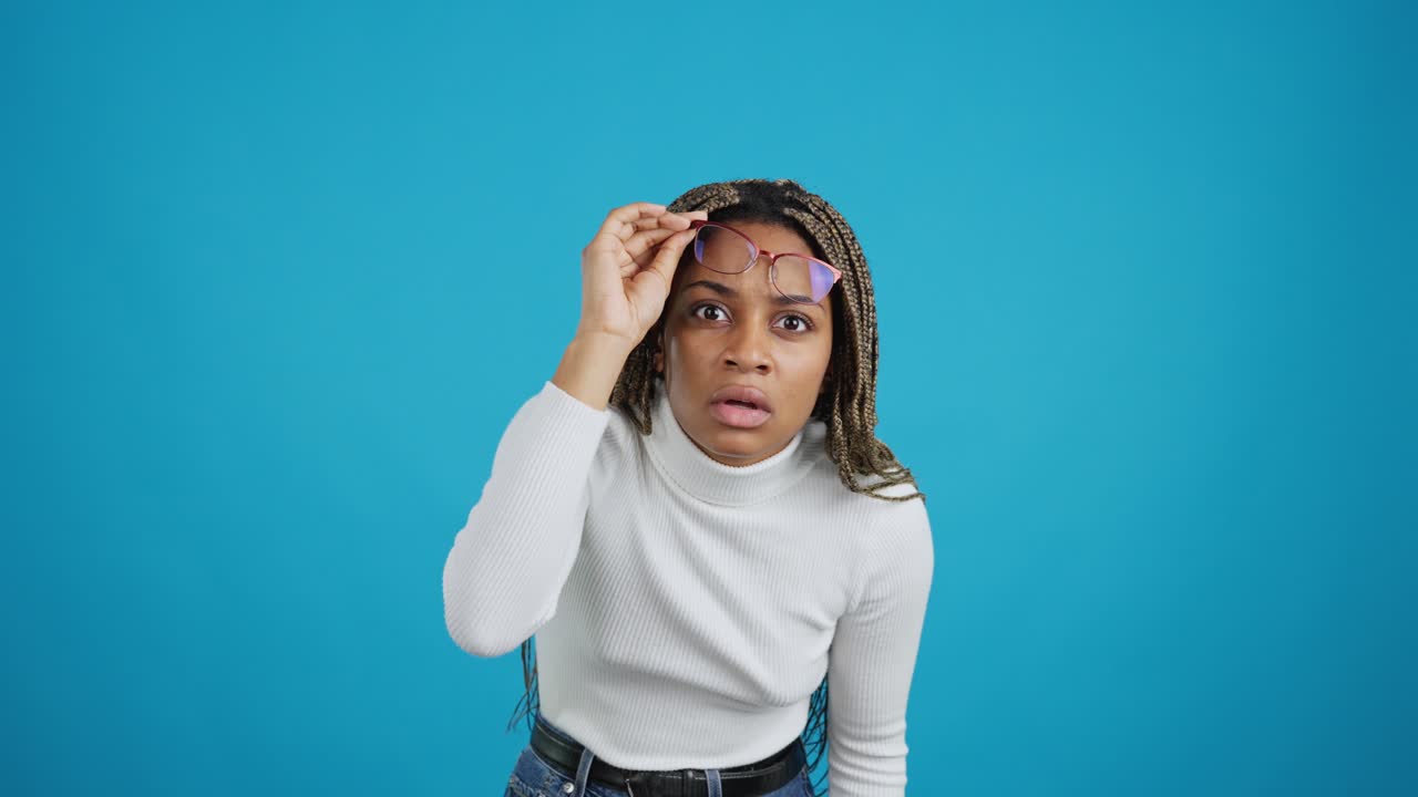 Young woman with a surprised or confused expression adjusting her glasses.