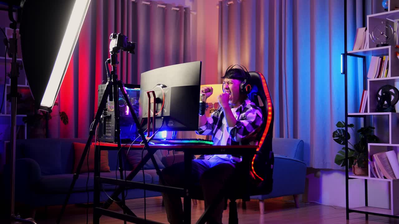 asian boy streamer gritando gol y bailando celebrando el juego ganador a través de la red en la computadora personal. videojuego de transmisión en vivo, escritorio iluminado por luz de tira led rgb