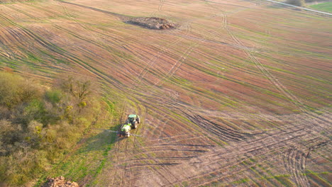 Toma-De-Seguimiento-Aéreo-Del-Tractor-Rociando-Fertilizante-En-El-Campo-Durante-El-Día-Soleado