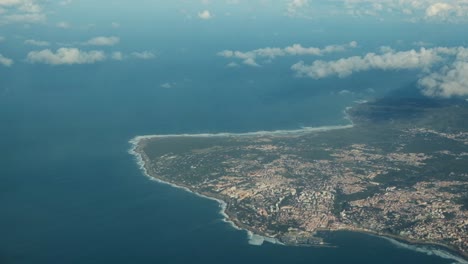 view of blue ocean water and country landscape from airplane porthole