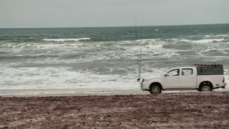 white truck on a sandy beach by the ocean