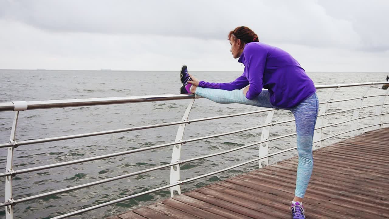 아침 일찍 바다  ⁇  해변에서 조 ⁇ 을 하기 전에 다리를  ⁇ 는 운동선수 여자