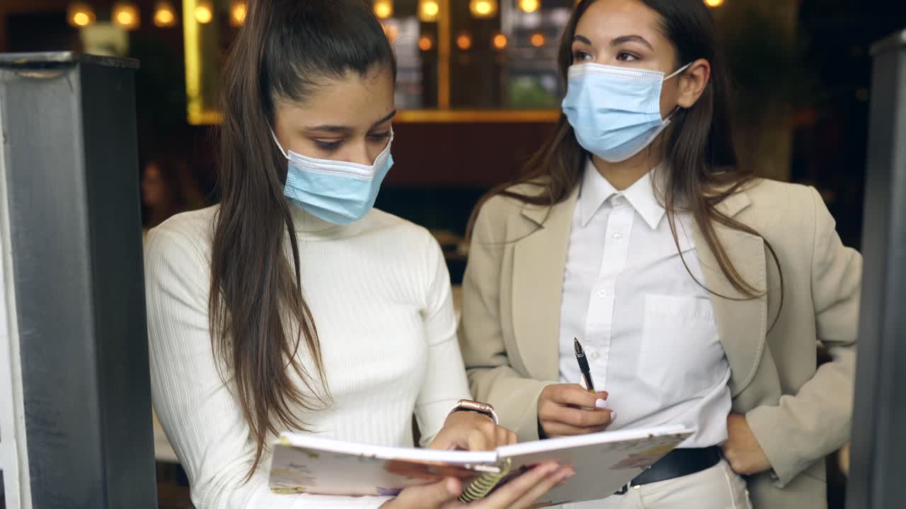 dos mujeres discutiendo en un café.