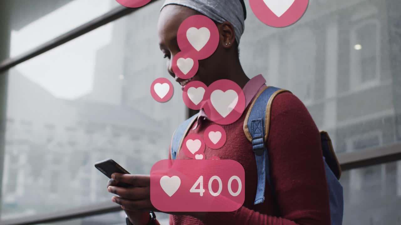 animación de los iconos del corazón de las redes sociales sobre una mujer afroamericana sonriente que usa un teléfono inteligente en la calle