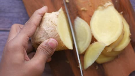 slicing ginger on a wooden cutting board