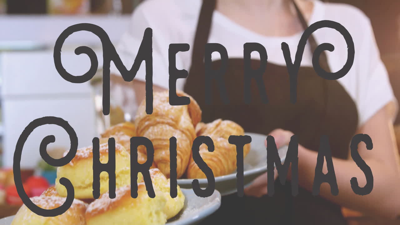 In kitchen, person holding plate of pastries with Merry Christmas animation
