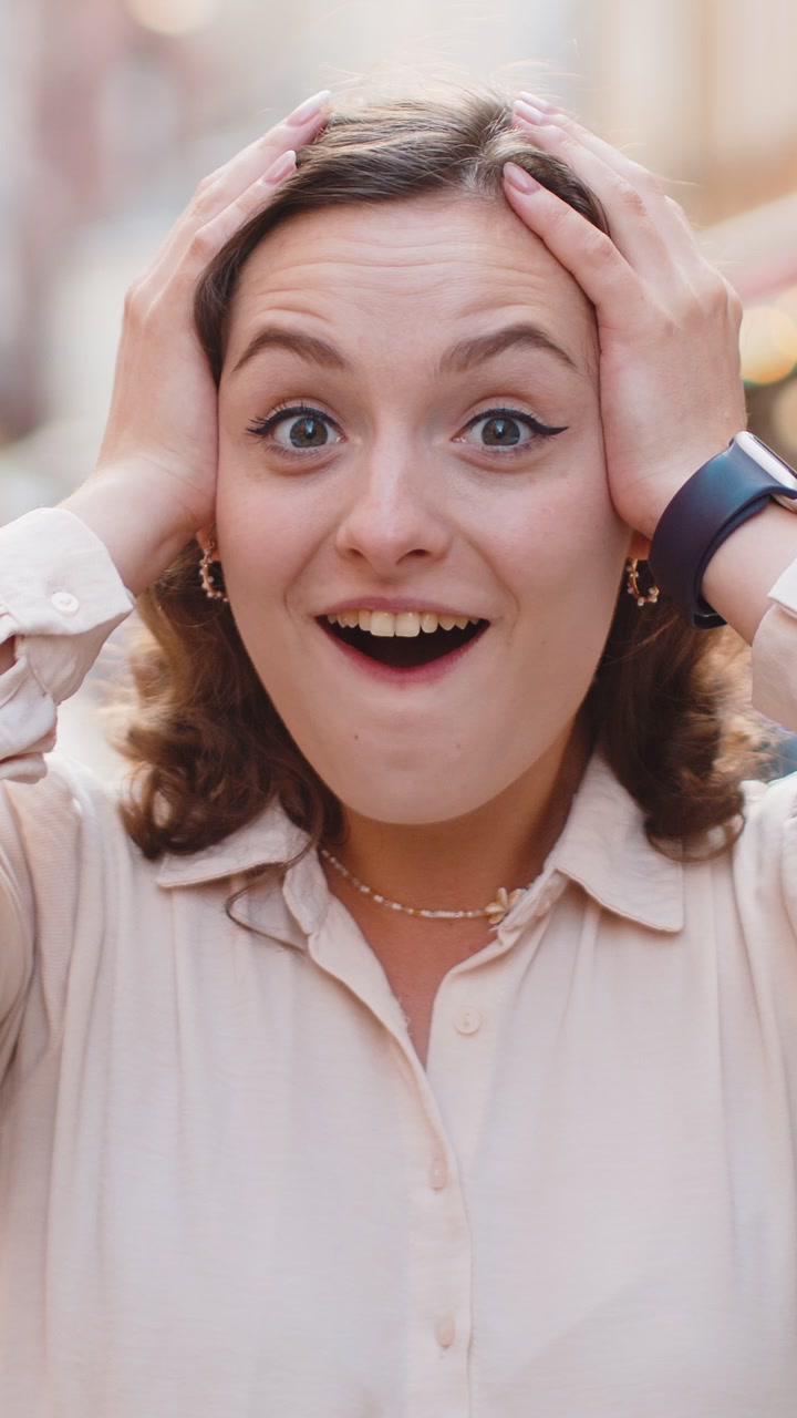 Young woman looking surprised at camera shocked by sudden win good victory news wow in city street