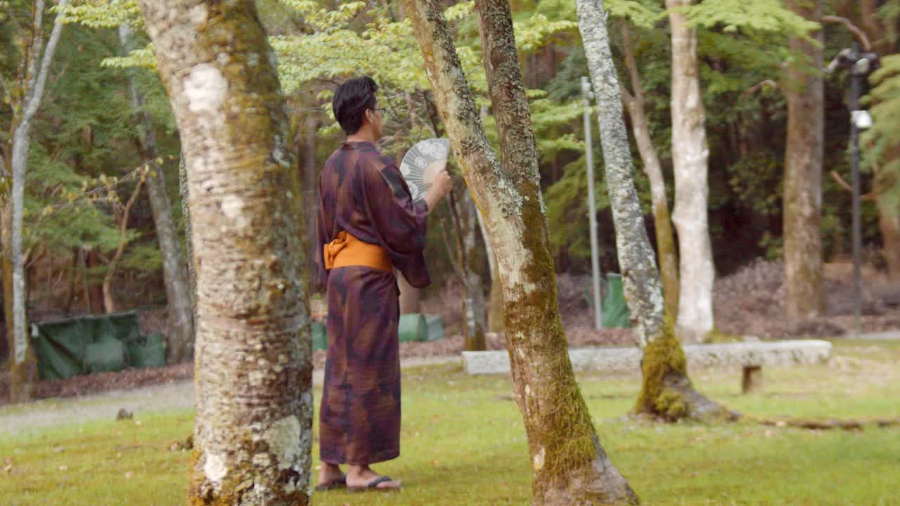 diapositiva de una persona que lleva un hakama de pie en un jardín japonés en kioto, japón 4k cámara lenta