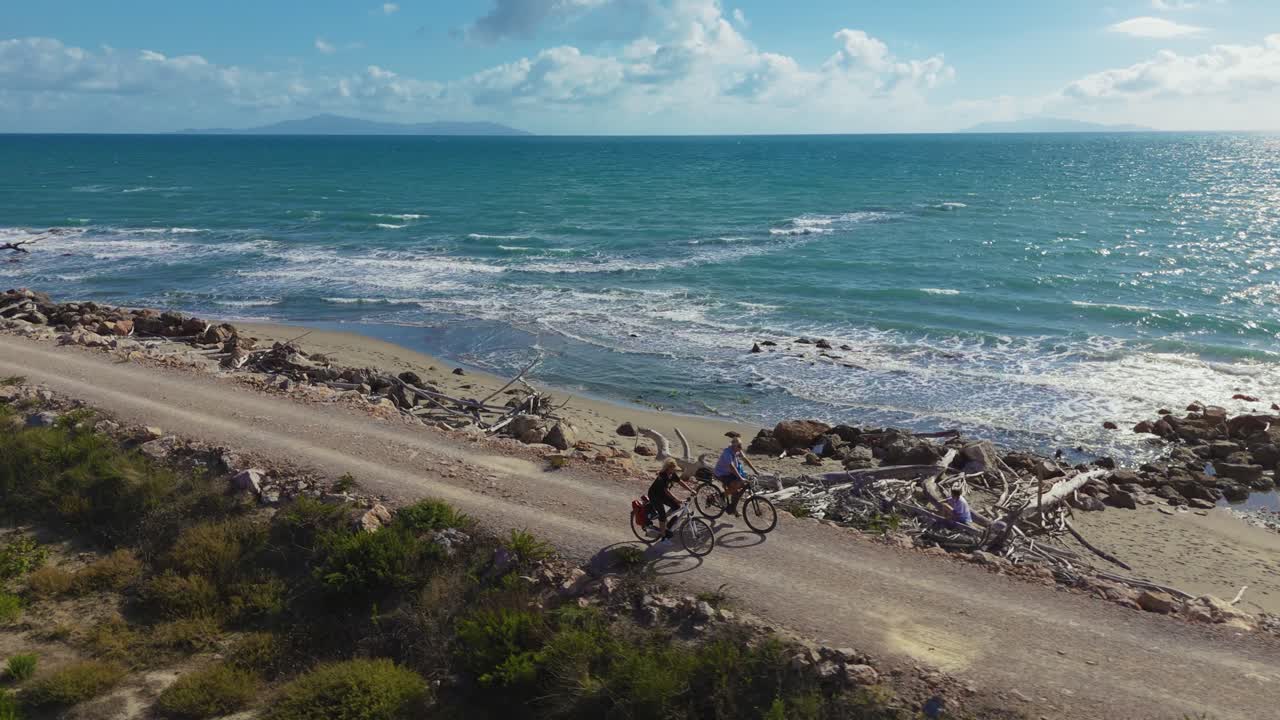 Senior couple man and woman riding electric pedelec bikes, active and sporty tour in Italy by the sea