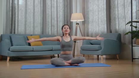 집에서 운동을 가르치는 동안 스포츠 옷을 입은 젊은 아시아 트레이너 여성이 말하고 어깨 십자 팔을하는 전체 시각