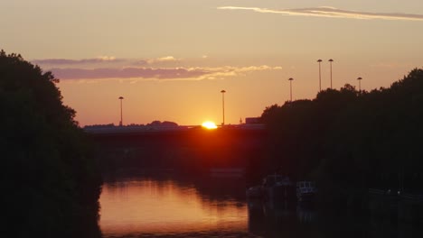 sunset in saarbrücken, germany, view of saar river at dusk, sun reflexion in water, car passing in front of the sun