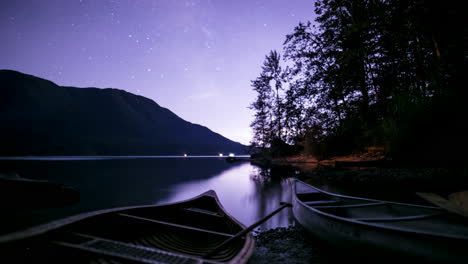 starlapse of canoes on a calm lake with mountains and trees