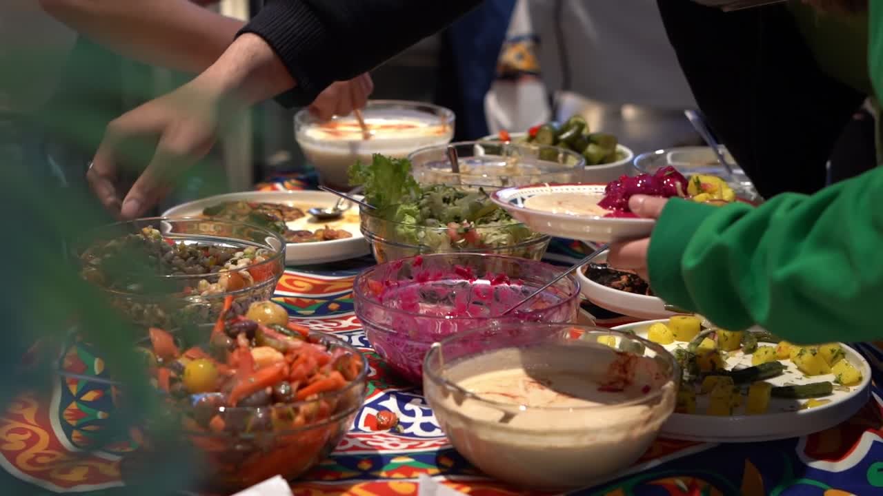 A group of people picking up salad for their food, close up shot, high angle shot