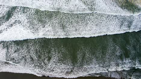4k aerial drone shot floating above ocean tide at seaside, oregon beach