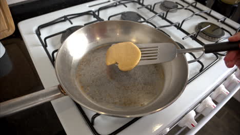 Slow-motion-of-an-unrecognizable-person-turning-over-a-heart-shaped-pancake-cooked-on-a-stainless-steel-skillet-on-Valentines-Day