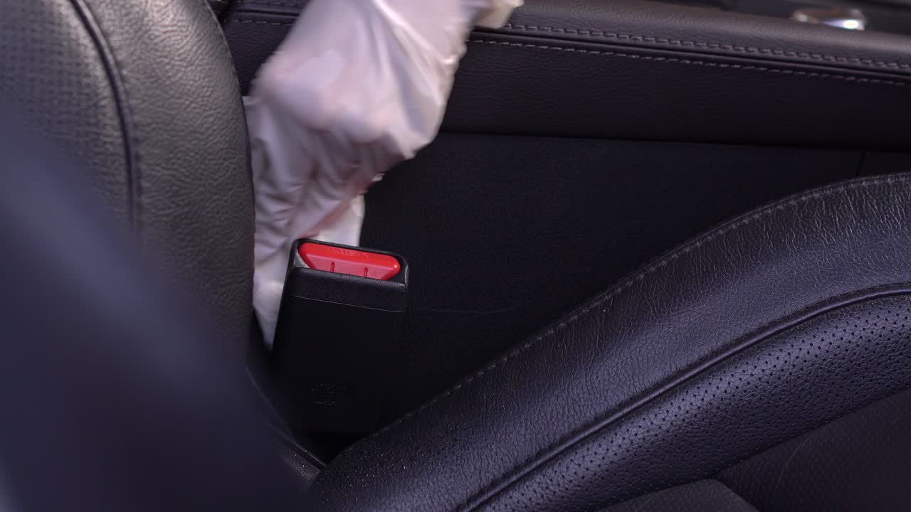 손에 탄력적인  장갑을 착용하여 자동차 좌석 벨트 버클을 청소, 자동차 내부의 스프레이 기, 소독제 기 (바이러스 확산, 오염된 표면, covid-19), 차량, 자동차 관리, 안전 우선, 자동차 보험