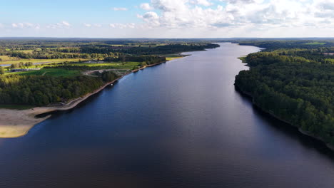likteņdārzs daugava ofrece una vista impresionante de un gran río rodeado de exuberantes bosques verdes. la escena evoca una sensación de paz y tranquilidad.