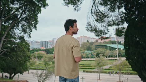 tranquil man drinking coffee in green park back view. relaxed guy enjoy beverage