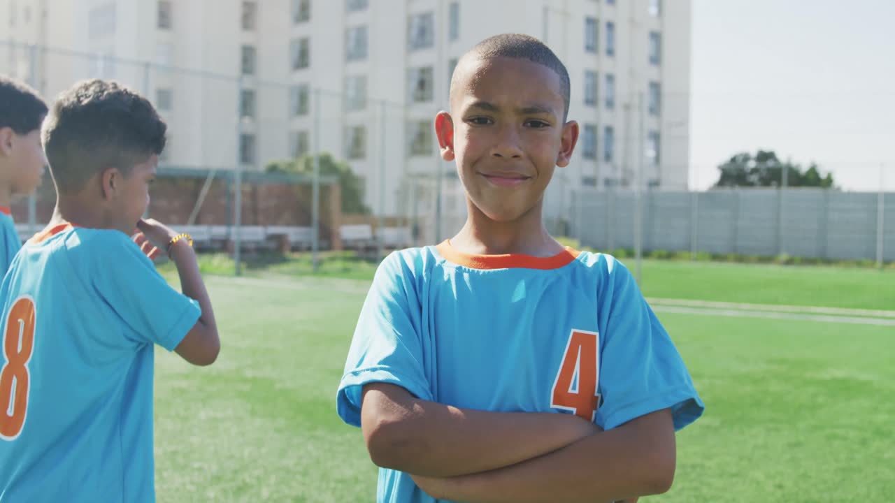 niño de fútbol afroamericano en azul sonriendo y mirando a la cámara