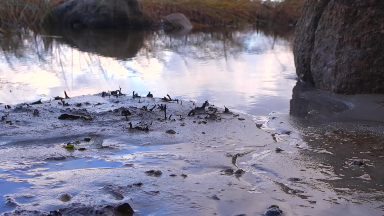 Close up view of ocean beach sea waves coming to a sandy beach shoreline in slow motion during sunset or dusk with the water reflecting the night sky in the bokeh blurry shallow depth backgrond
