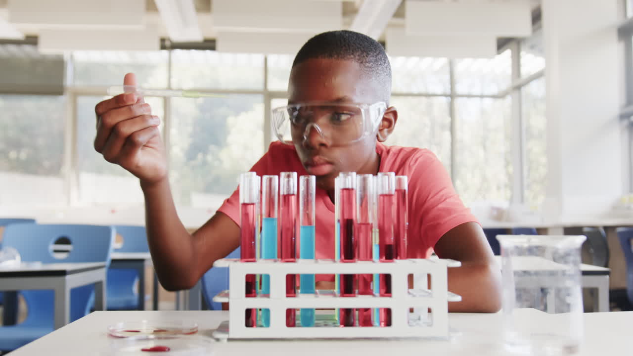 In school, boy conducting science experiment with test tubes in classroom laboratory