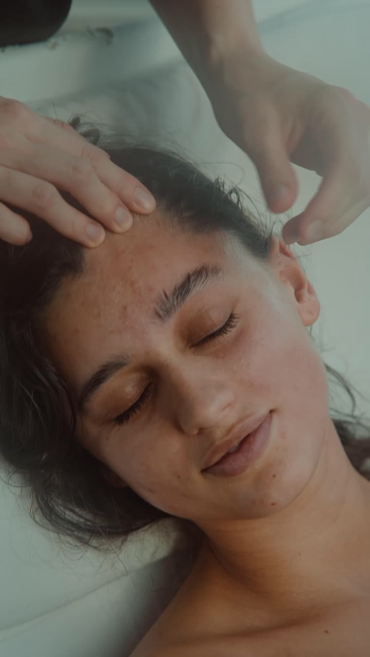 Mujer joven recibiendo un masaje facial relajante en un spa
